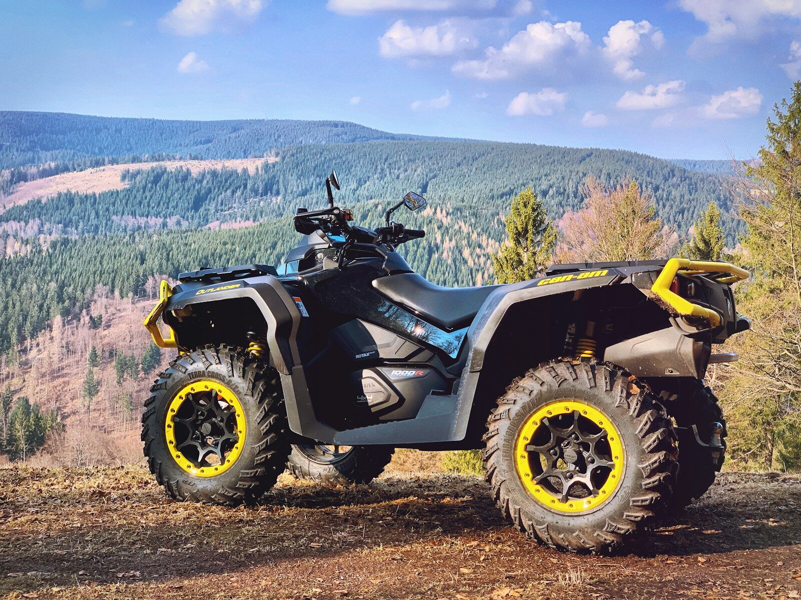 yellow and black atv on brown field under blue sky during daytime